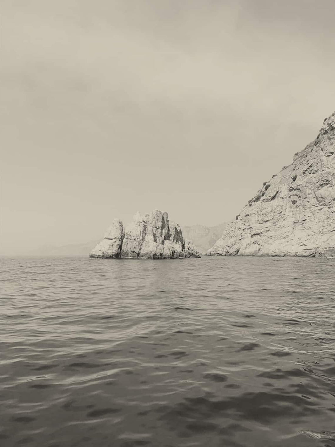 Black and white image of a rock in the ocean